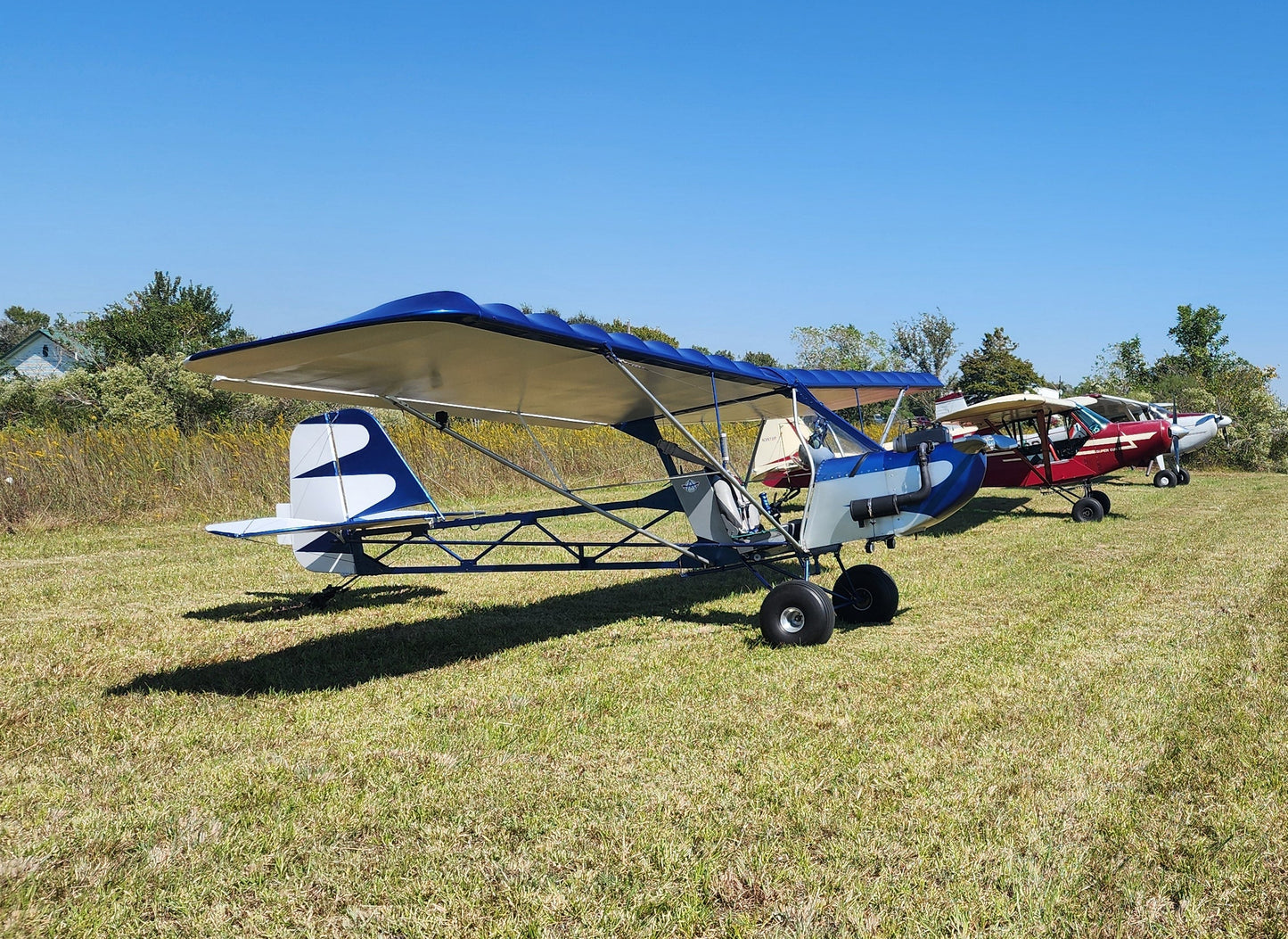 Small airplanes on a grassy field with a clear blue sky.